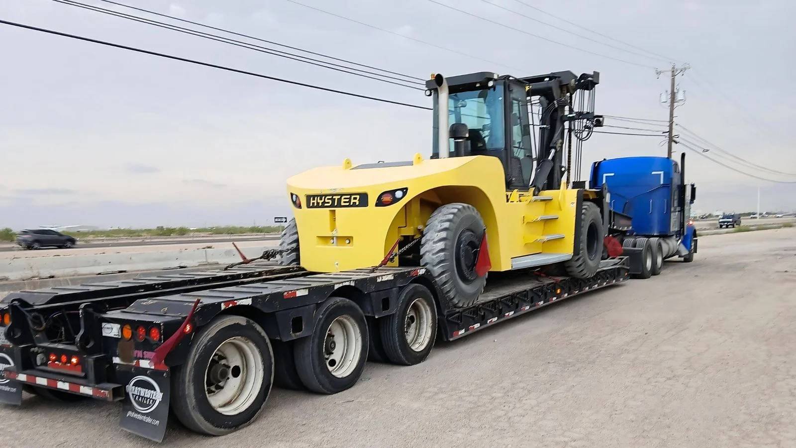 Step deck trailer hauling construction equipment through Southern California