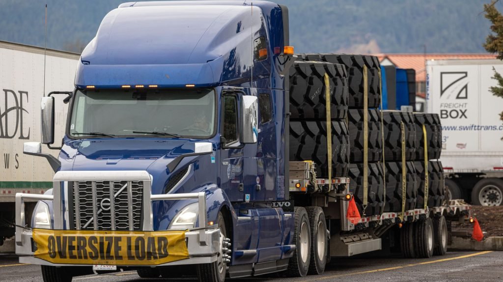 Oversized tires loaded on a step deck trailer for machinery parts transport from Los Angeles