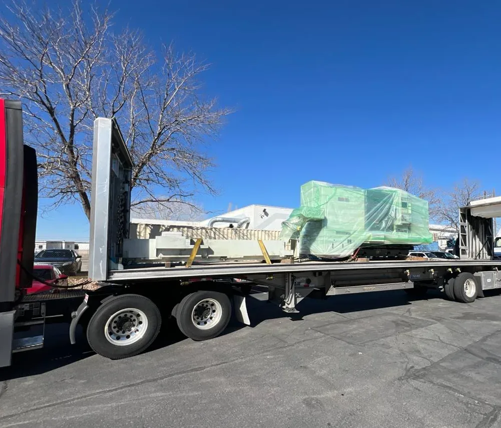 Shrink wrapped CNC machine on a flatbed Shrink wrapped machine and its base frame loaded on a spread axle flatbed trailer