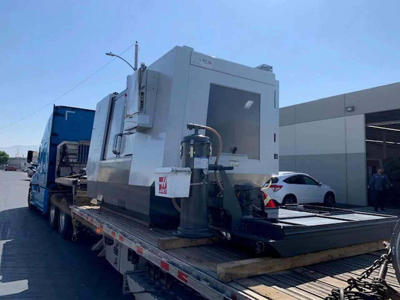 CNC Machine Secured on a Step Deck Trailer CNC machine chained on the lower deck of a step deck trailer