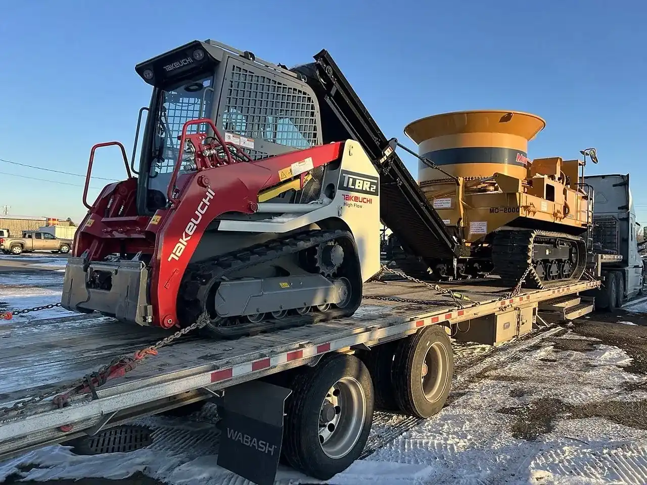 Compact track loader and attachment on a flatbed