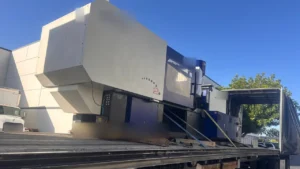 Conestoga machinery transport Los Angeles: injection molding machine on a flatbed Conestoga with the tarp rolled back