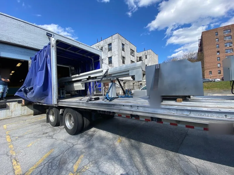 Conestoga trailer with the curtain pulled back to unload a machine at an urban loading dock