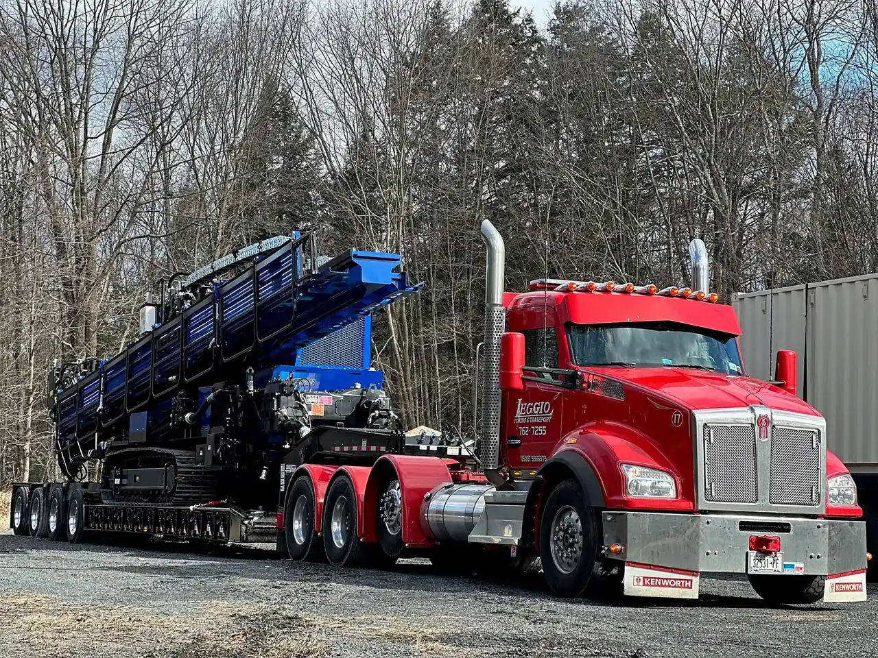 Drill rig on a lowboy behind a red truck