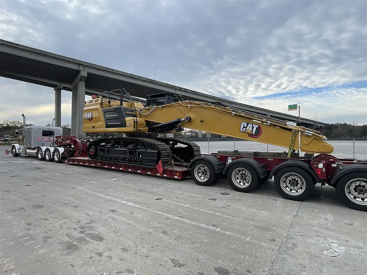 Excavator on an RGN trailer under a freeway overpass