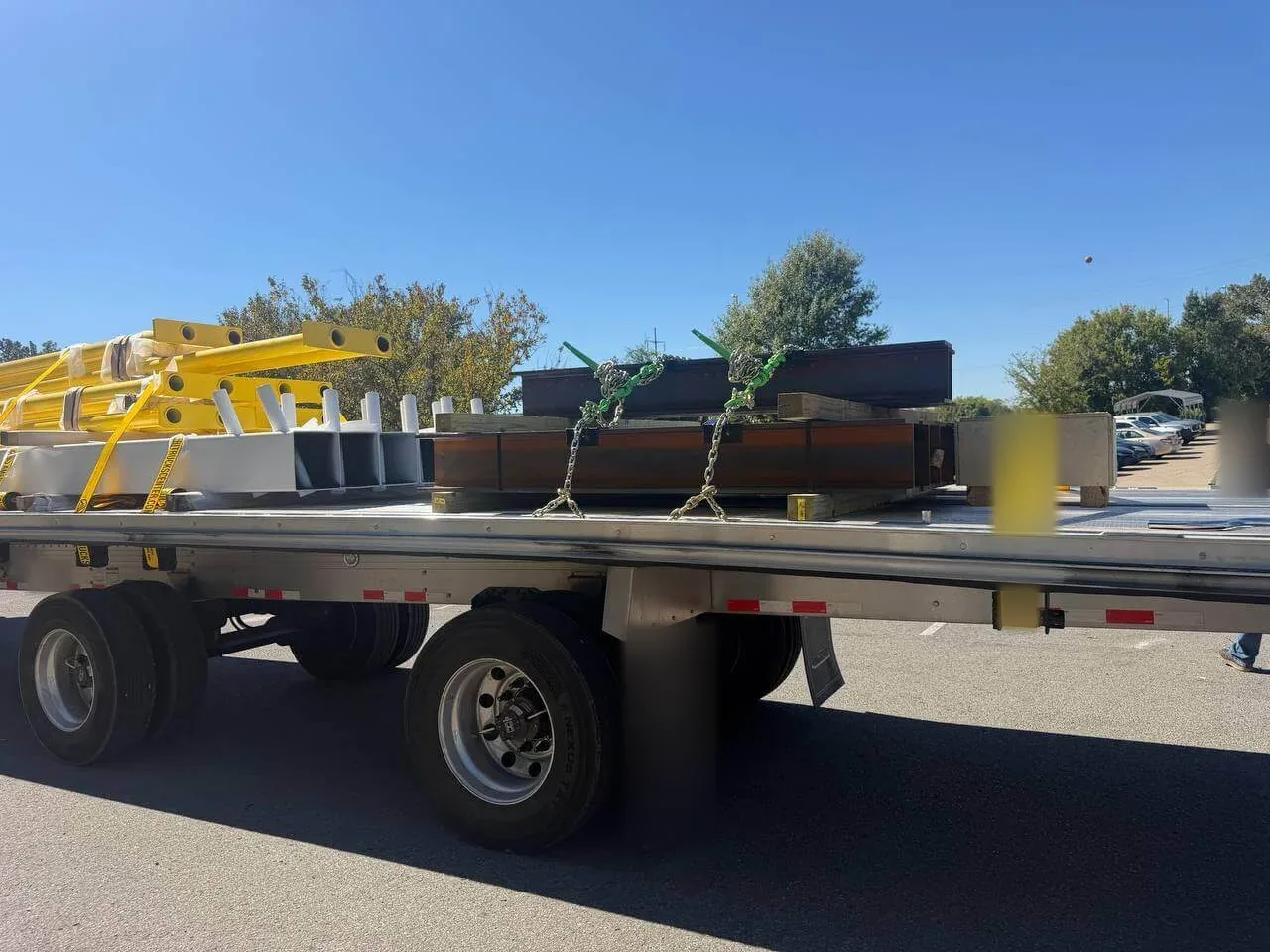 Team flatbed Los Angeles to Chicago freight: powder coated steel and steel beams chained and strapped on a flatbed