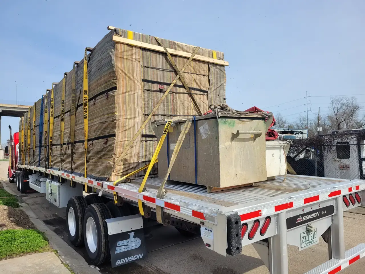 Tall load wrapped in tarps and strapped on a flatbed trailer