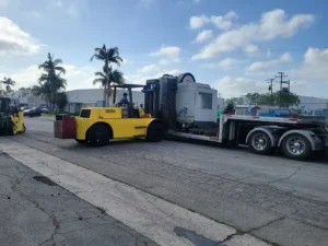Forklift loading a CNC machine onto a double drop trailer in Los Angeles