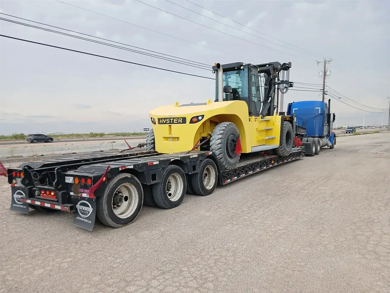 Heavy forklift chained on an RGN trailer