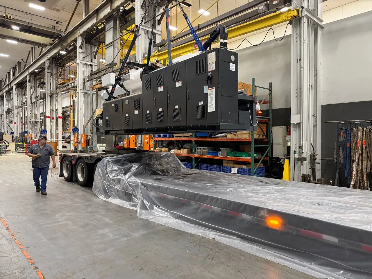 Injection molding machine loaded on a lowboy trailer indoors