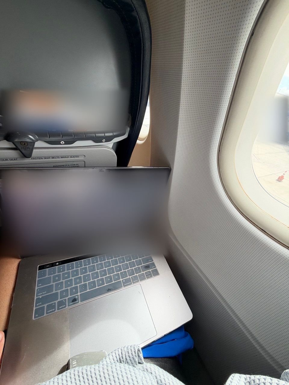 Los Angeles freight broker answering freight emails on a laptop during a flight, window seat view