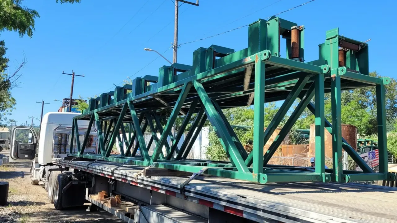 Green steel conveyor support structure loaded on a flatbed trailer