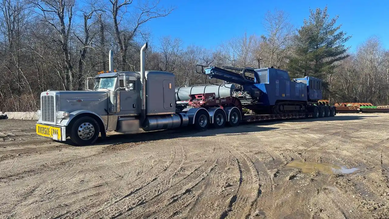 Tracked Drill Rig on a Multi Axle RGN Semi truck pulling a multi axle removable gooseneck trailer loaded with a tracked drill rig, with an oversize load banner