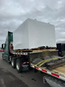 Shrink-wrapped machine on pallets loaded on a step deck trailer