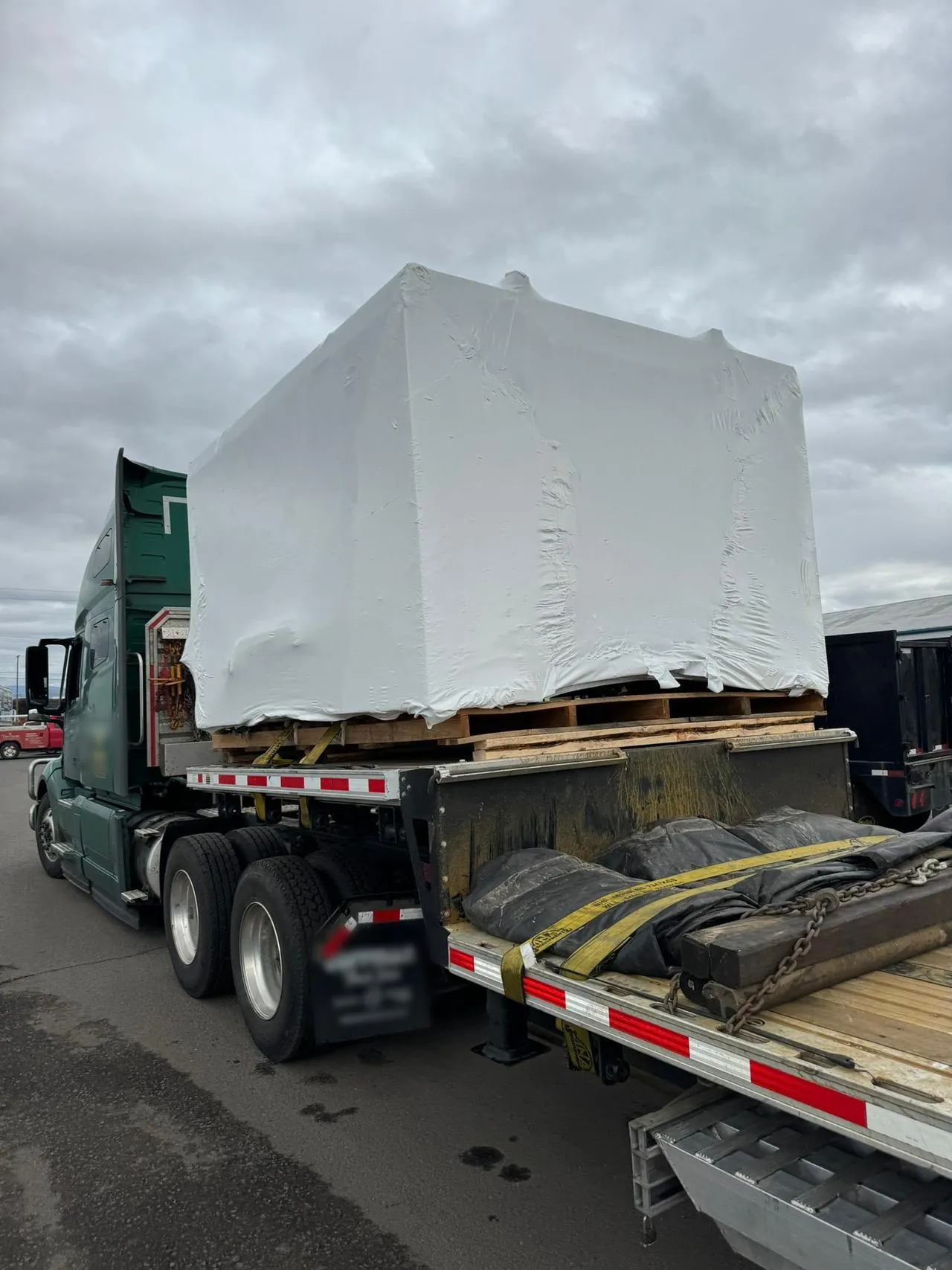 Shrink-Wrapped Machinery on a Step Deck After Transload Shrink-wrapped machine on pallets loaded on a step deck trailer