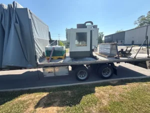 Small vertical machining center loaded on a Conestoga trailer at pickup