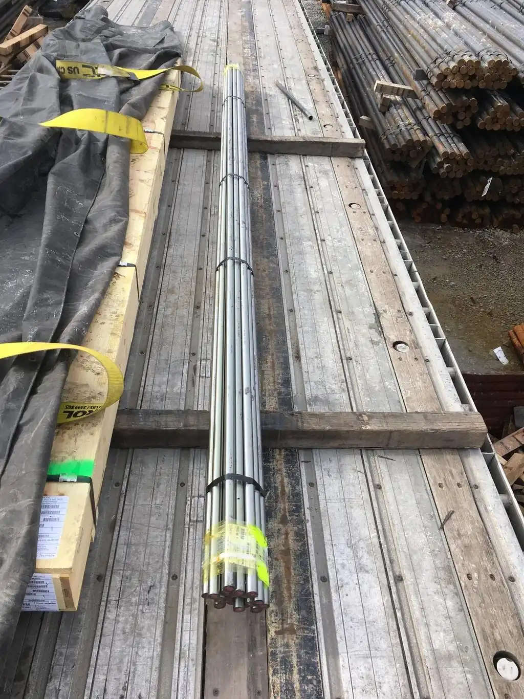 Steel Bar Bundles Strapped on a Flatbed Deck Steel bar bundles strapped to the wood deck of an open-deck trailer