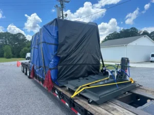 Tarped CNC machine chained on an RGN step deck trailer